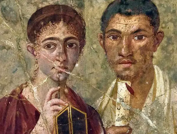 Ancient Roman wall painting of a woman holding a stylus and wax tablet next to a man holding a scroll, both looking forward. The artwork shows signs of aging and cracks.