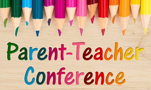 Parent Teacher Conference text with colorful pencil crayons on a wood desk