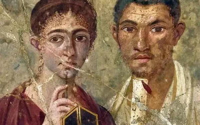 Ancient Roman wall painting of a woman holding a stylus and wax tablet next to a man holding a scroll, both looking forward. The artwork shows signs of aging and cracks.